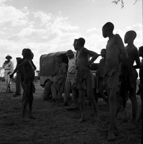 Group of men standing with John Marshall and two other expedition members next to the expedition Jeep