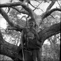 Woman standing in front of a tree, holding her hand over her mouth