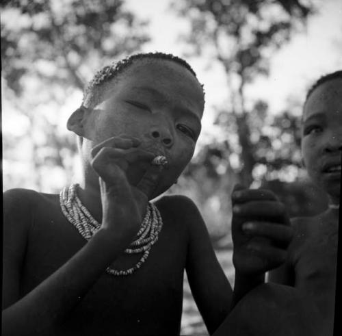 Boy smoking a cigarette, with another child next to him
