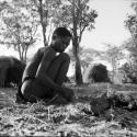 /Gunda tending a fire, with mangetti nuts on the ground next to him