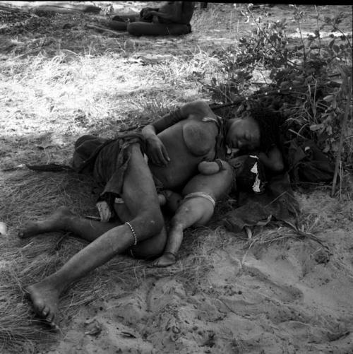 Woman sleeping with her baby in the shade