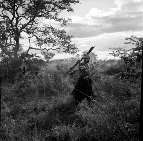 Woman carrying a piece of wood, with a group of people sitting in the background