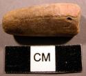Ground stone bead, uneven, tubular, one flat surface, worn