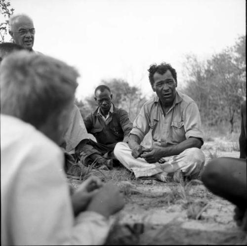 Wilhelm Camm sitting, talking with a group of expedition members including Laurence Marshall and John Marshall