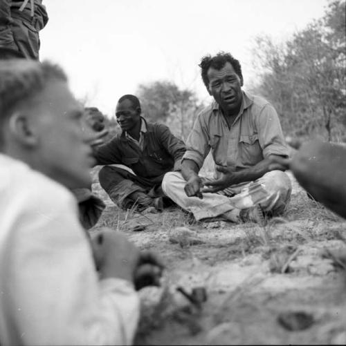 Wilhelm Camm sitting, talking with a group of expedition members including John Marshall