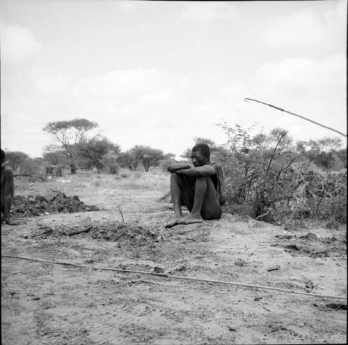 Man sitting, with a spring hare pole on the ground in front of him