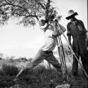 John Marshall filming the sky or top of tree, with another expedition member standing next to him