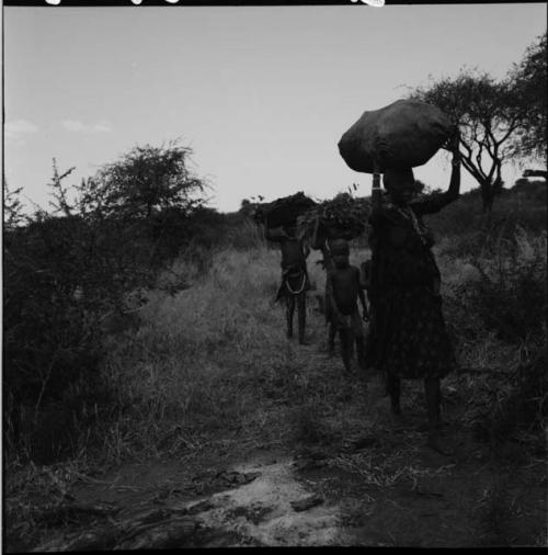 Women carrying bundles on their heads, with a child walking between them