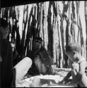 Two women and a child working on corn inside a skerm