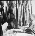 Two women and a child working on corn inside a skerm