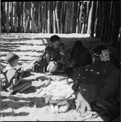 Women and children working on corn inside a skerm