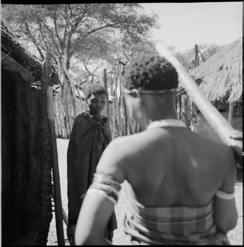 Two women standing outside a skerm looking down at another woman who is not visible