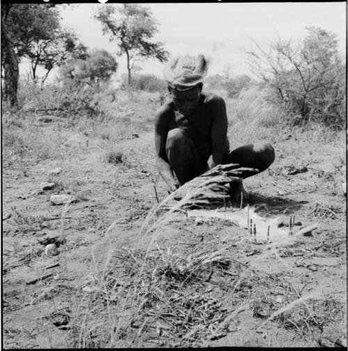 ≠Toma wearing a hat, scraping a small animal skin