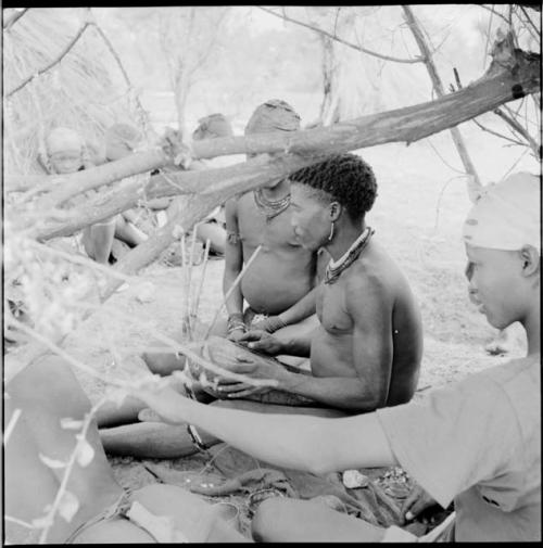 Man playing the //guashi, sitting with a group of people