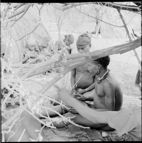 Man playing the //guashi, sitting with a group of people