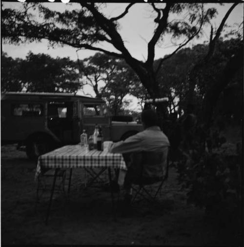 Expedition staff member sitting at a table, with the expedition Land Rover in the background