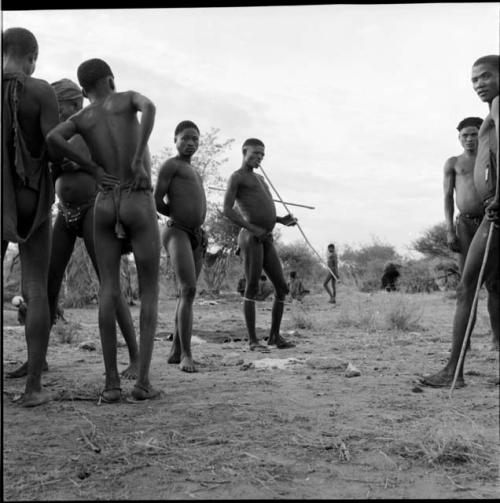 Group of men standing, some holding thin sticks