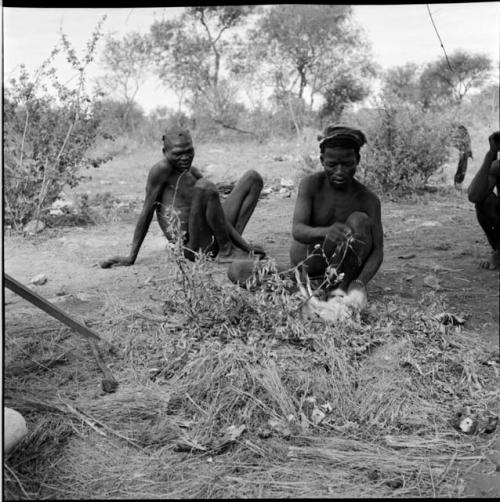 ≠Toma skinning an animal, with another man sitting behind him