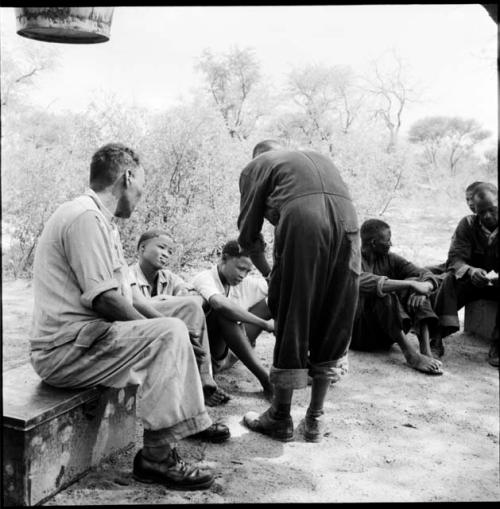 Men sitting with expedition members in the expedition camp