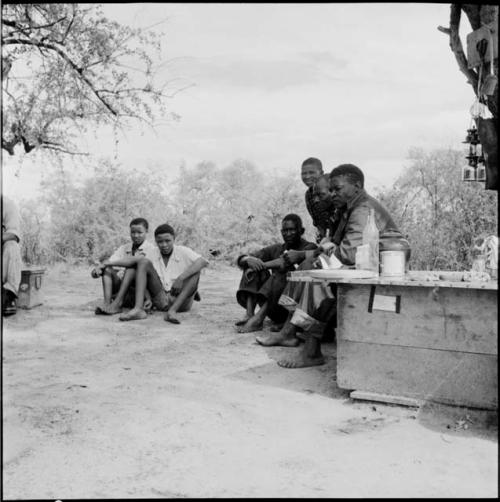 Men sitting with expedition members in the expedition camp