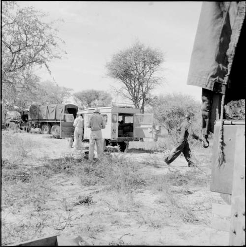 Expedition members standing and walking next to the Land Rover