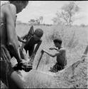 Gau (husband of Be and Khuan//a) and two other men working on a dead wildebeeste