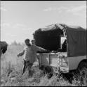 Man standing next to the back of the expedition Jeep