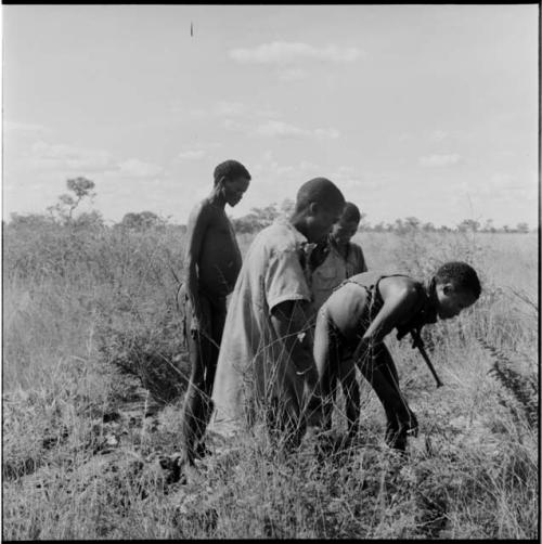 Four hunters standing, looking at the ground