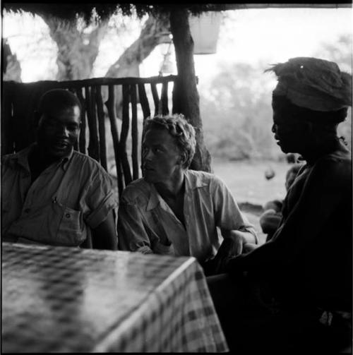 ≠Toma sitting at a table in the expedition camp with Wilhelm Camm and John Marshall