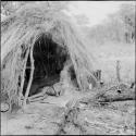 Child sleeping in the opening of a skerm, with a fire burning in front of it