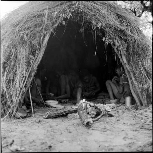 Family sitting inside their skerm, working, with a fire laid outside the entrance