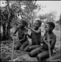 Three boys playing !ó'm!hú / !’Om g!xuni / ’Ai kota !U!u g!xuni / N!aih //’an (the porcupine game, also known as the axe game, assegai game or war game)