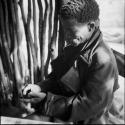 ≠Toma wearing a coat, looking at a beetle in his hand, sitting at a table in the expedition tent, helping expedition members to identify insects