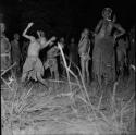 Two boys dancing in the middle of a circle of women at a night dance