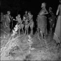 Two boys dancing in the middle of a circle of women at a night dance