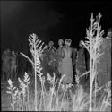 Group of women standing, clapping and singing, with a group of boys standing near them