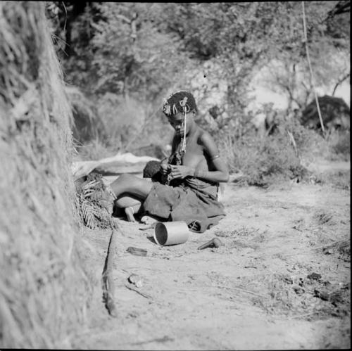 Woman sitting next to a skerm working on something, with a child sitting between her legs