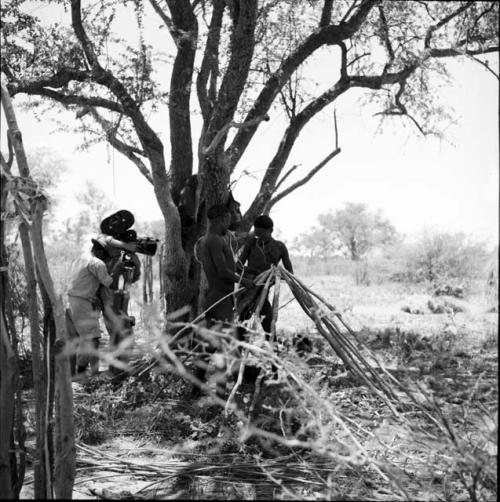 Two men lashing the poles of a skerm together, with John Marshall filming them