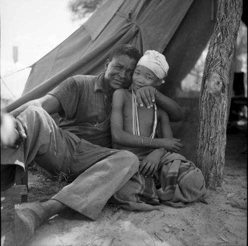 N!ai sitting with an expedition member outside the expedition tent