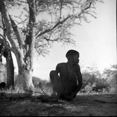 Man squatting, starting a fire