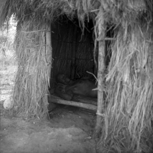 Man sleeping on a raised bed inside a skerm