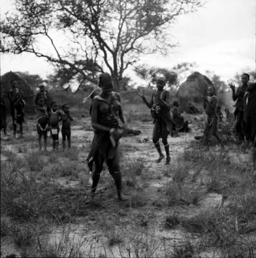 Two women playing tamah n!o’an (ball game), one carrying a baby on her back