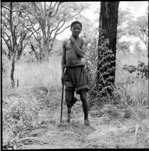 "Short /Qui" standing, leaning on his stick