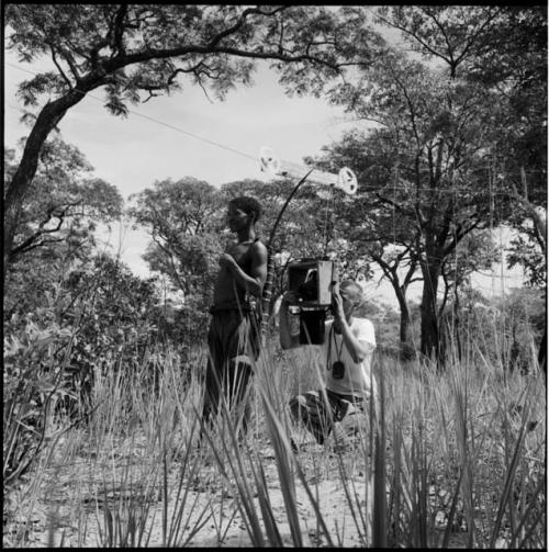 "Short /Qui" carrying his hunting equipment on his back, being filmed by John Marshall, using a pulley to take a close-up