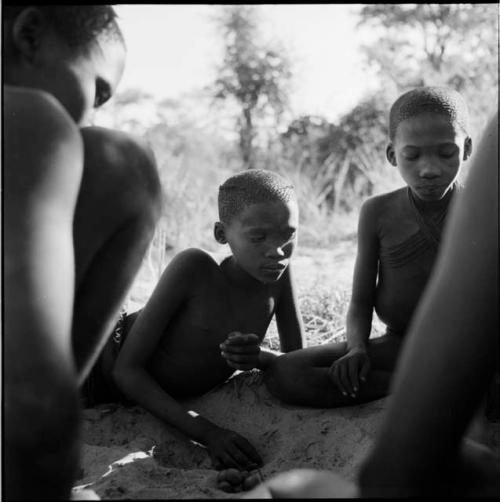 Group of boys playing /Ui (the counting game) in the sand