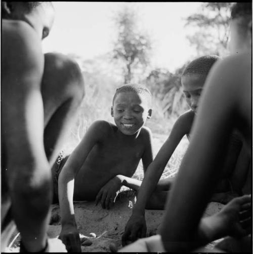 Group of boys playing /Ui (the counting game) in the sand