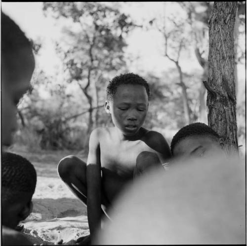 Boy playing /Ui (the counting game) with a group of boys