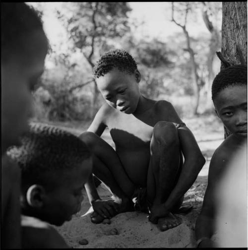 Boy playing /Ui (the counting game) with a group of boys