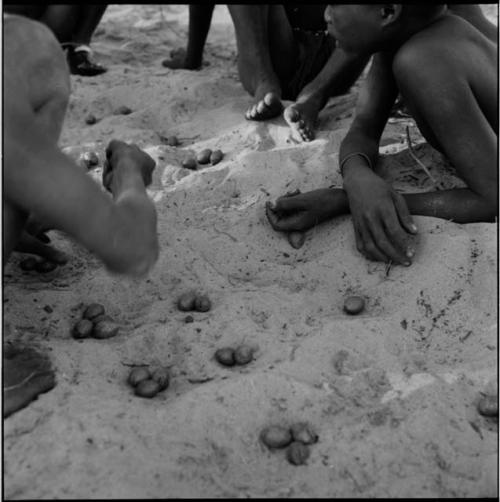 Group of boys playing /Ui (the counting game) in the sand, close-up