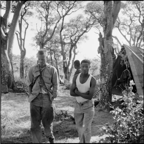 John Marshall and another expedition member walking, with a tent in the background